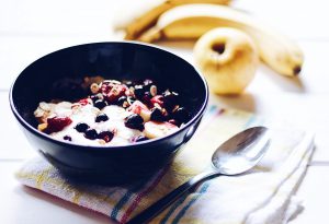 bol de muesli avec yaourt et pomme et bananes posées à côté